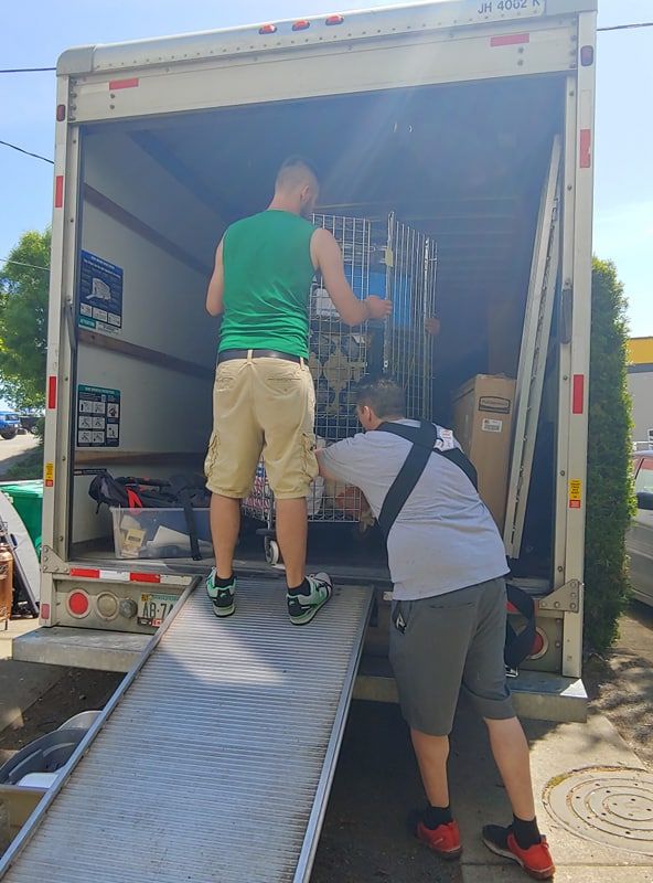 Two movers loading a box truck from the ramp